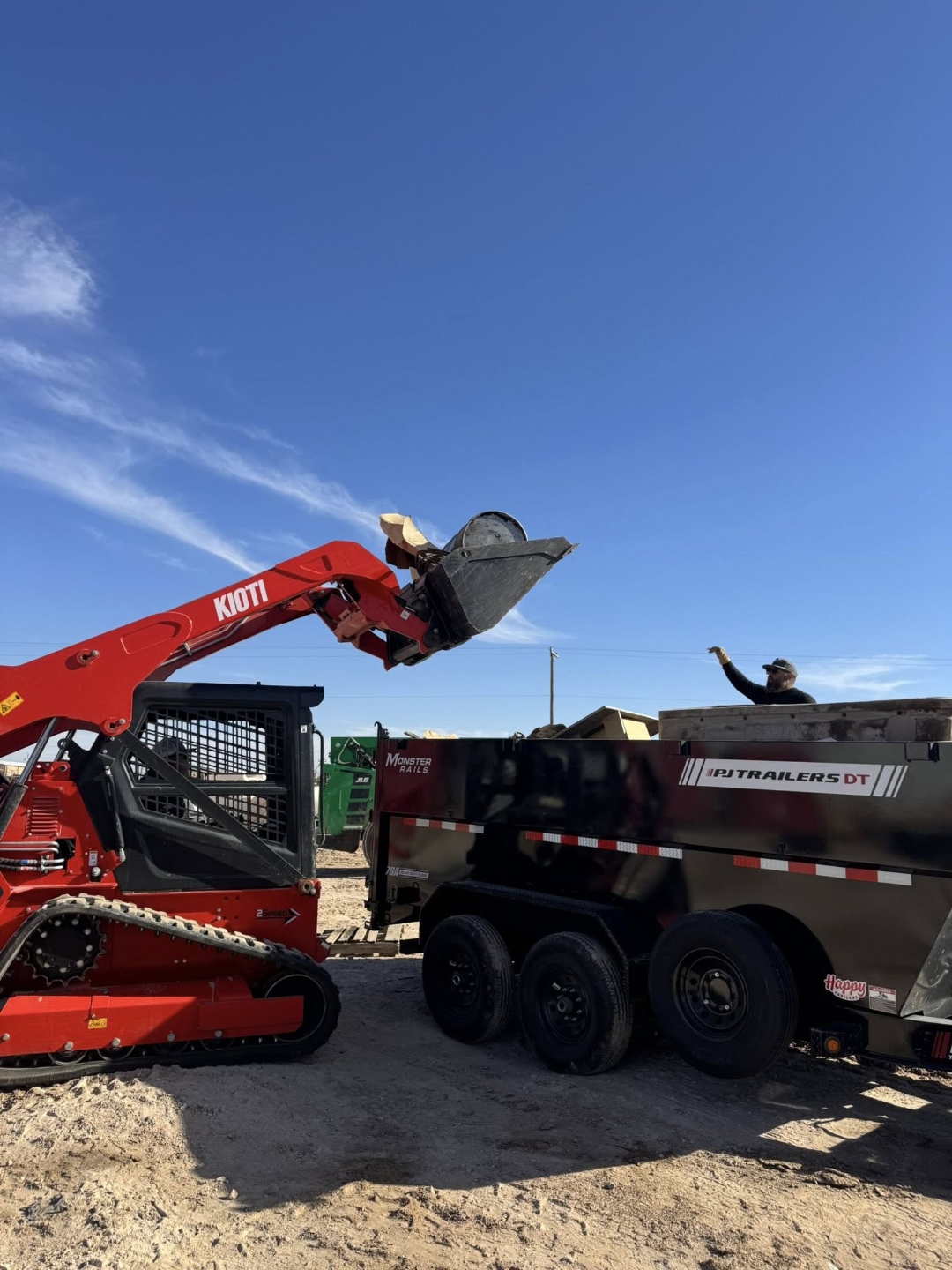 JNKD Hauling & Cleanouts Kioti skid steer loading debris into dump trailer
